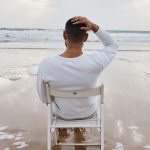 a man sits on a chair at the beach