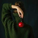 woman holds an apple behind her back